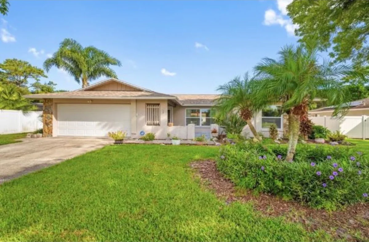 Single-story home with a two-car garage, palm trees and a landscaped front lawn