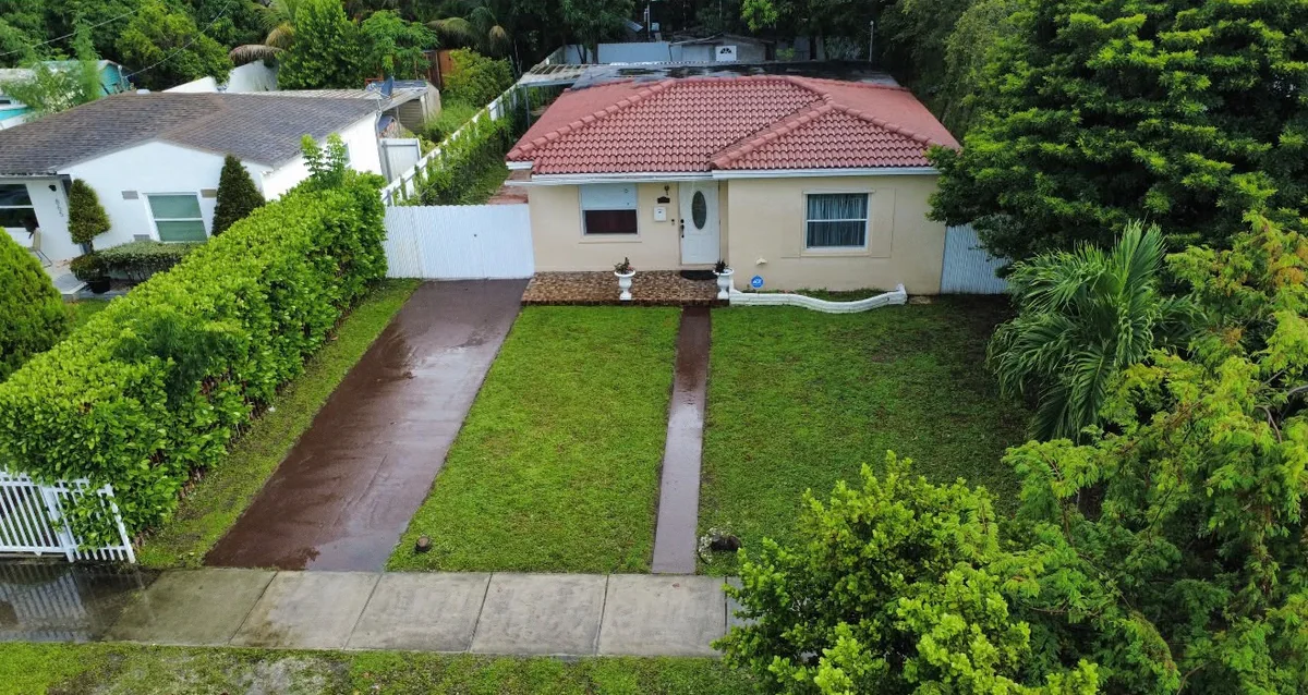 Aerial view of a concrete single-family home with a red tile roof and front lawn on NE 133rd Street, Miami