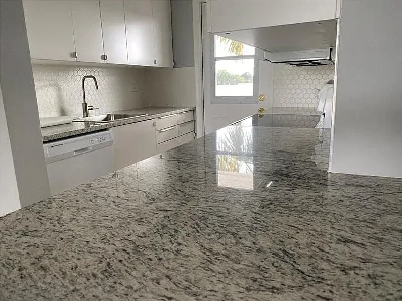 Updated condo kitchen with granite countertops, white cabinets and hexagon tile backsplash